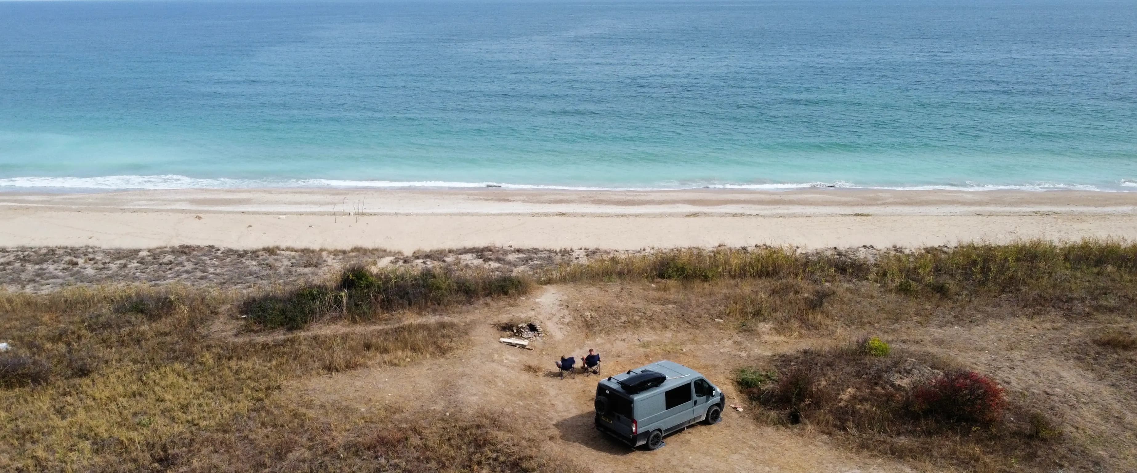 Campervan parked on a scenic beach with mountains in the background