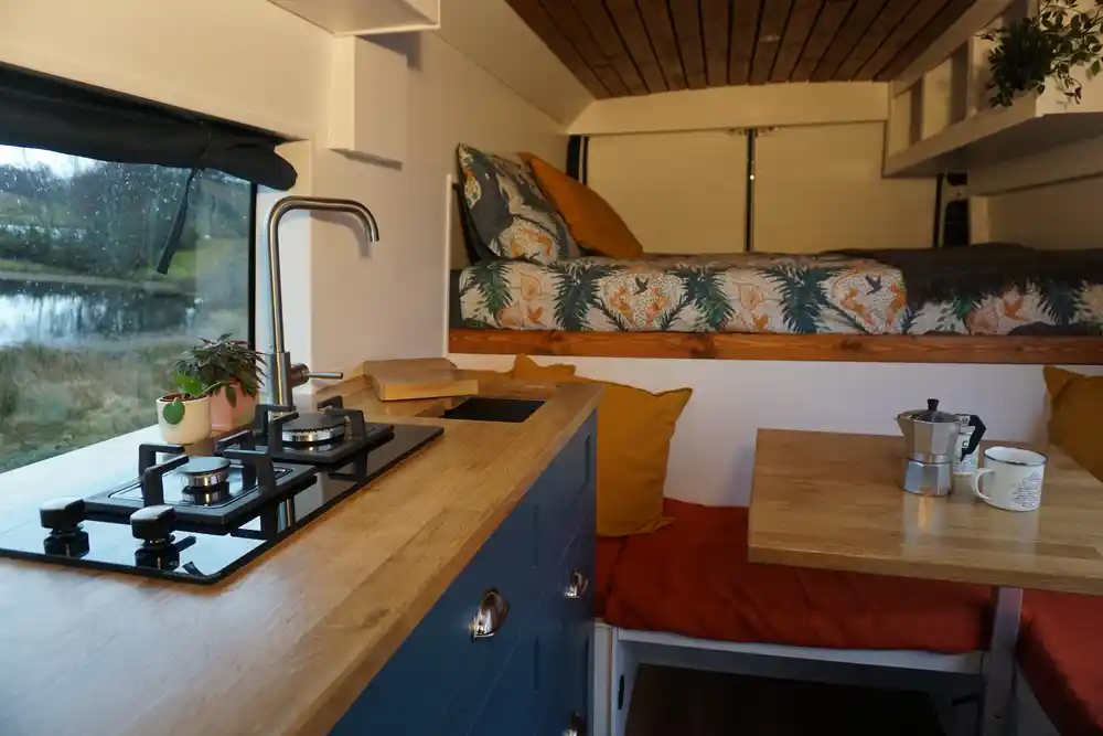 Sprinter campervan interior showing kitchen with oak worktop and fixed bed